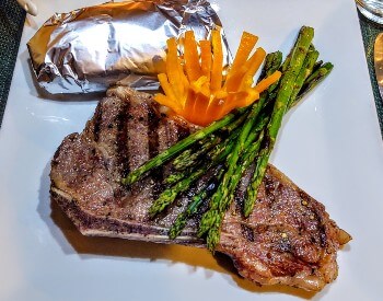plate with a steak, asparagus, baked potato and a sliced pepper