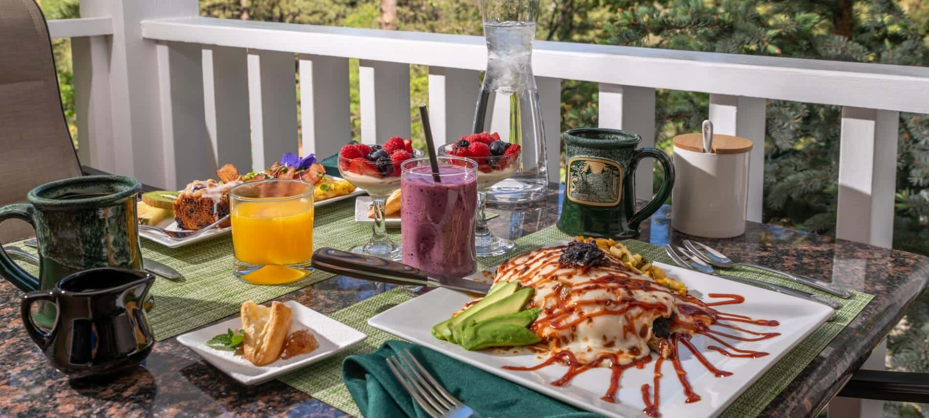 Glass and wicker table outdoors on a patio with plates of breakfast food, cups of orange juice and coffee and dishes of fruit