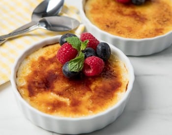 small round white dish with fresh fruit atop of creamy pudding with caramelized sugar topping