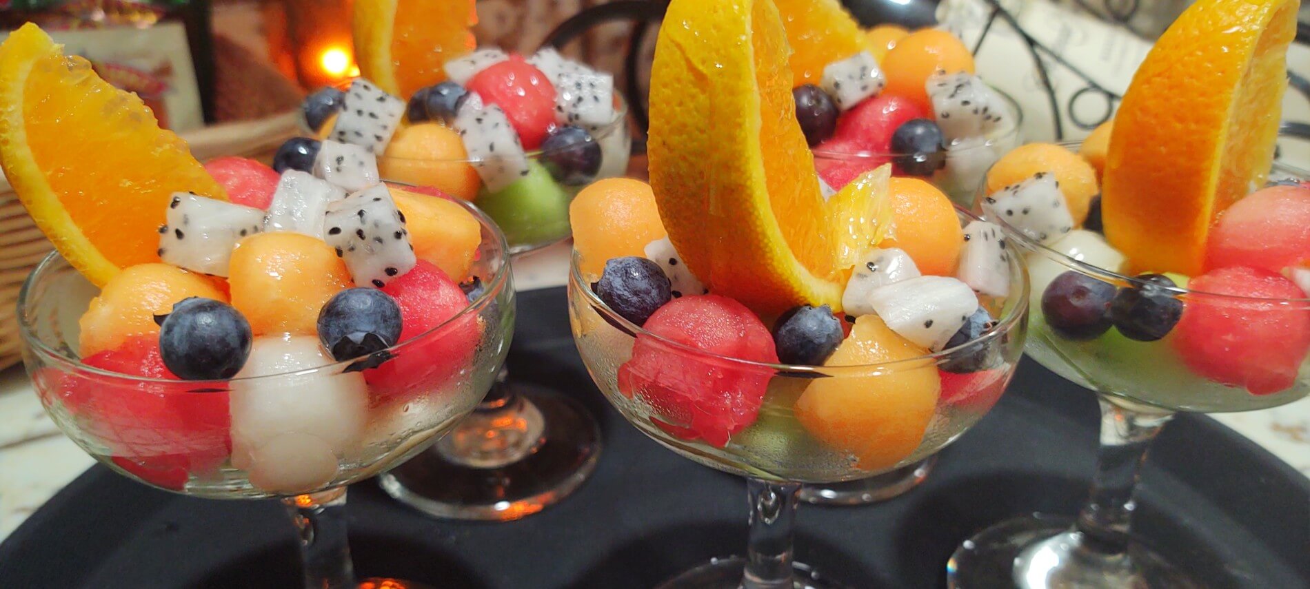 parfait glasses with melon balls, dragon fruit, blueberries and orange wedges