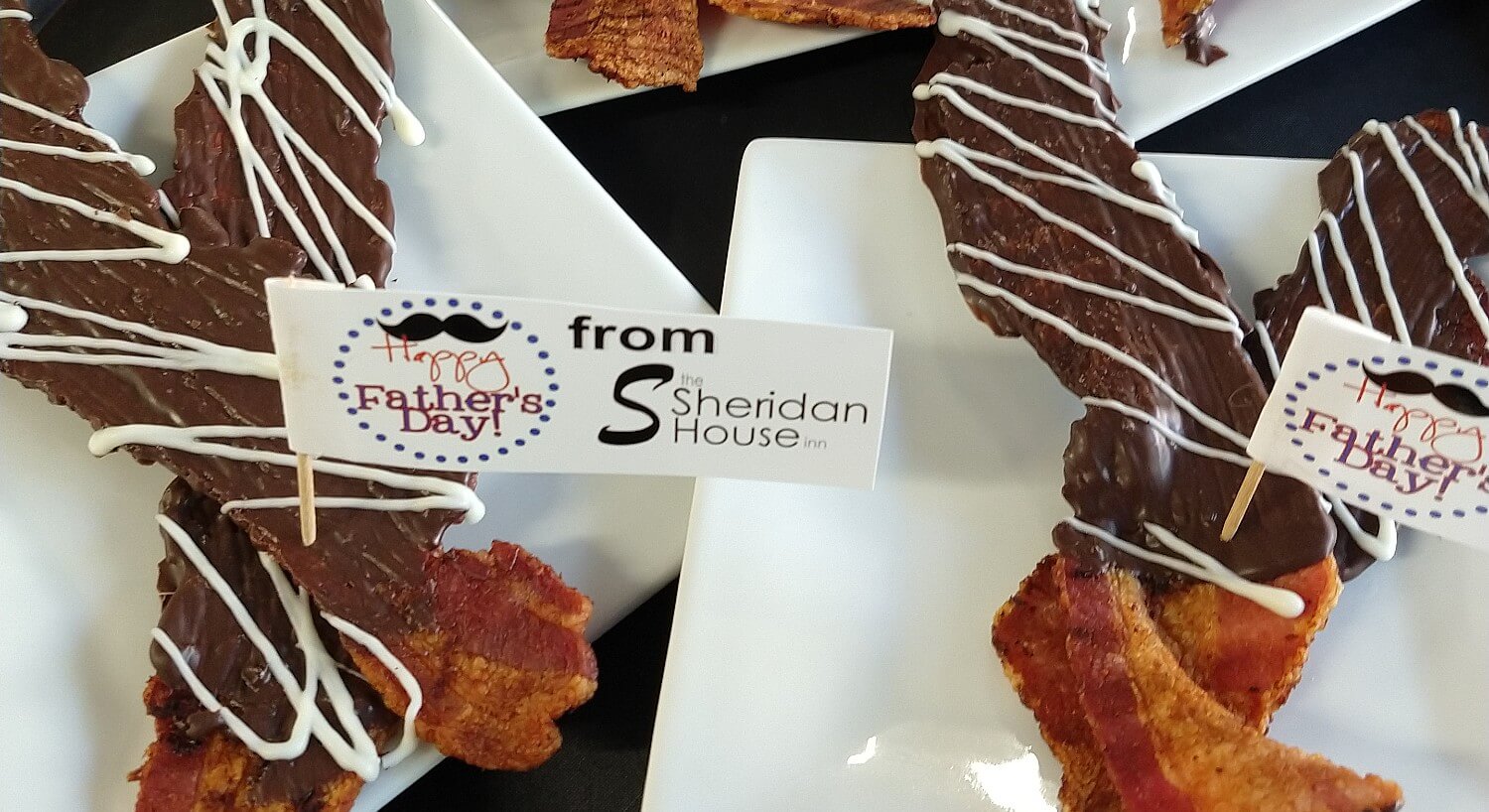 Pieces of chocolate covered bacon on square white plates with tags for Happy Father's Day