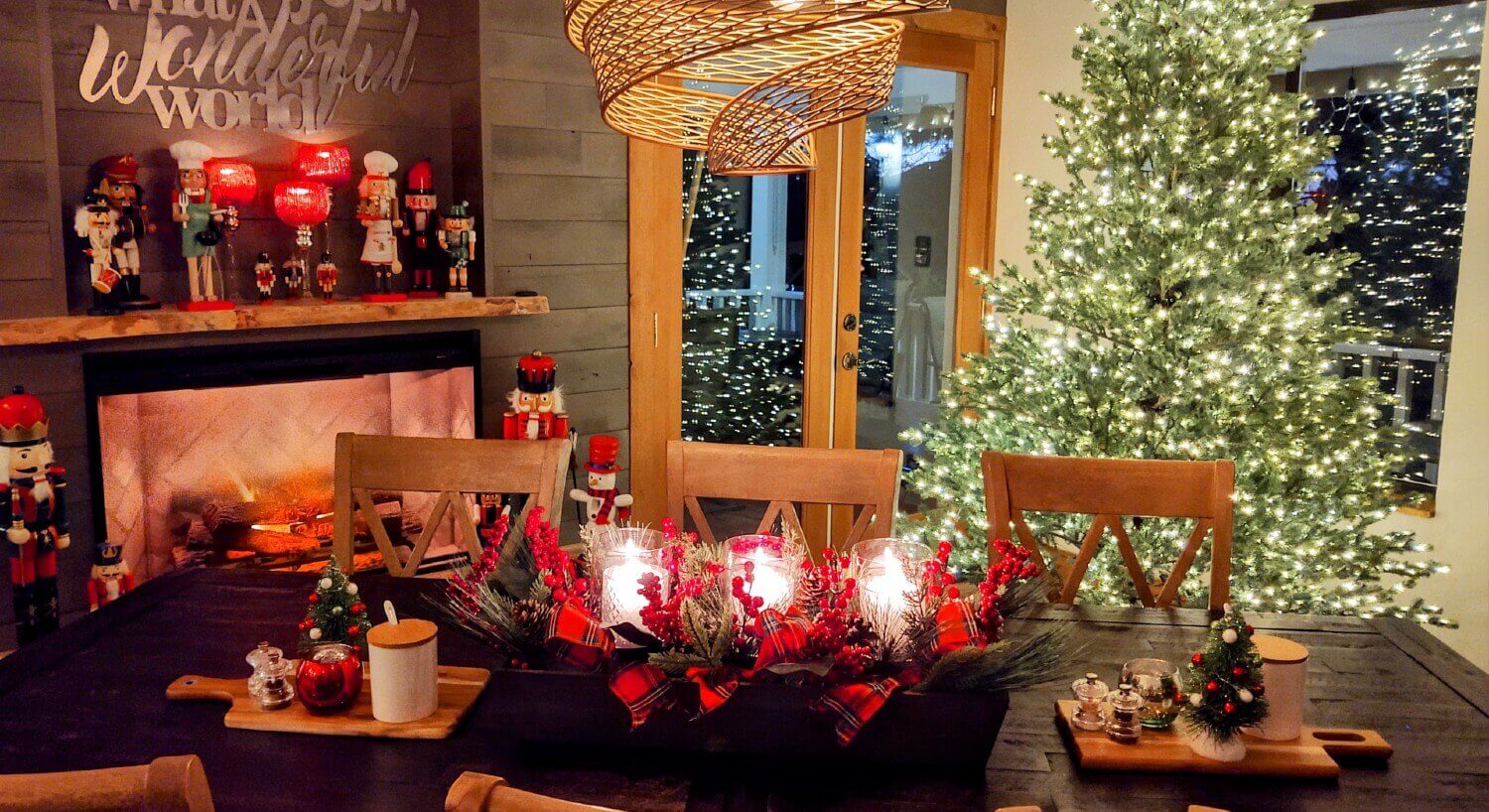 rectangular table set with Christmas decorations , mantel with nutcrackers above burning fire, Christmas tree with white lights