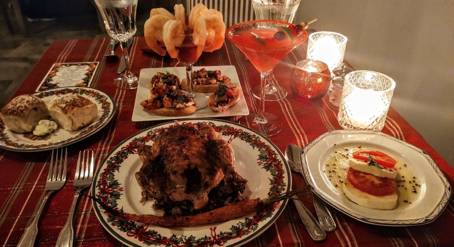 cornish hen dinner on Christmas plates served with rolls, cocktail shrimp and drinks