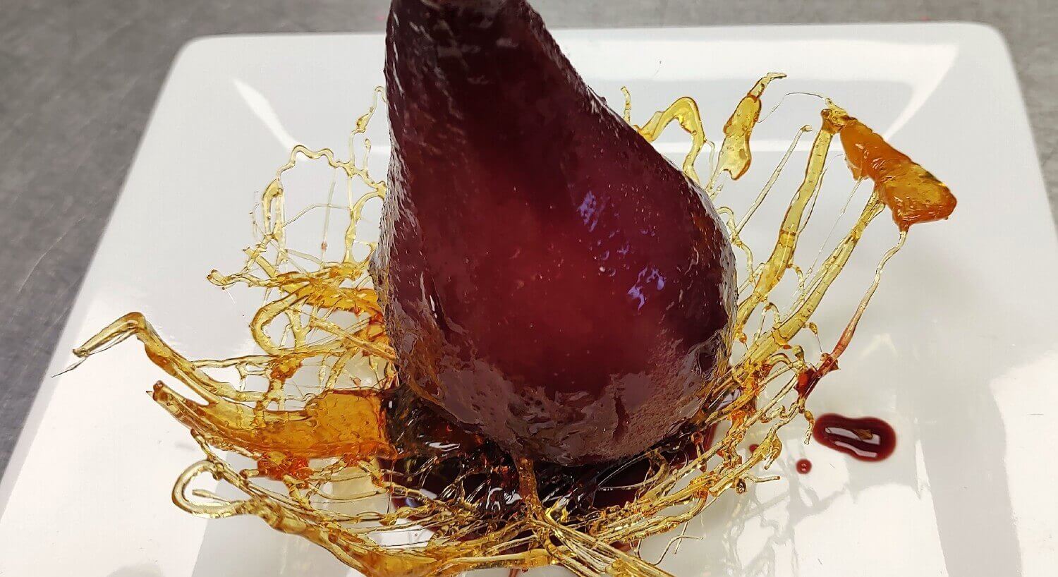 pear sitting unright on white porcelain dish drizzled with honey