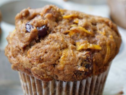 Delicious carrot and fruit muffin with a white wrapper on a white plate