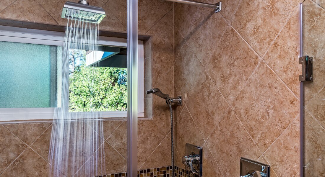 Luxurious stand up shower with window to the outside, glass doors and modern rainfall showerhead