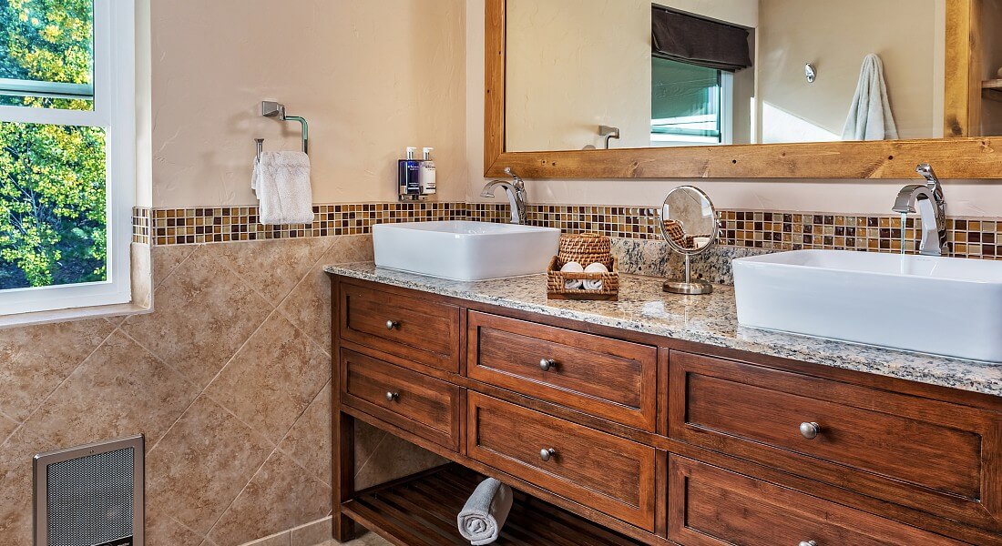 Long wood vanity with granite countertop, two square sinks with silver faucets and large framed mirror