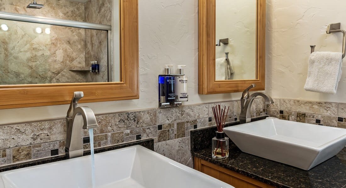 Modern square white sinks on two granite-topped vanities with wood framed mirrors above