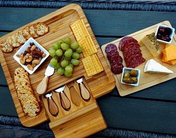 Two wooden charcuterie boards or meat, crackers, cheeses and fruit on a table