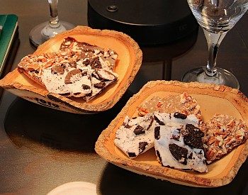 Two decorative bowls with varieties of chocolate bark and two tall wine glasses