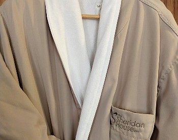 Front of a luxurious beige and white robe with an inn logo hanging on a hanger