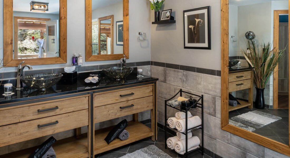 Spacious bathroom with two square sinks atop a wooden vanity and two large framed mirrors