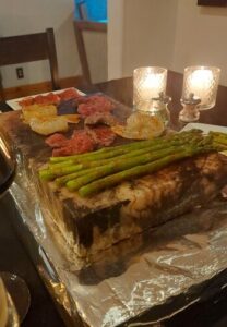 salt block with asparagus, beef and shrimp cooking on it