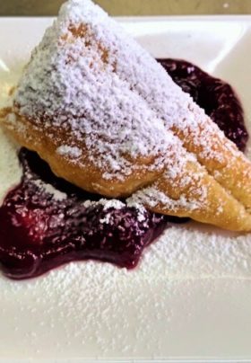 puff pastry triangle with blueberry sauce and powdered sugar