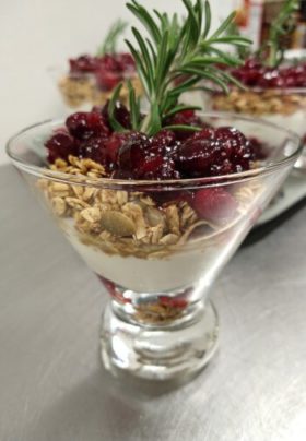 glass dish with yogurt, granola and cranberry sauce with rosemary sprig on top