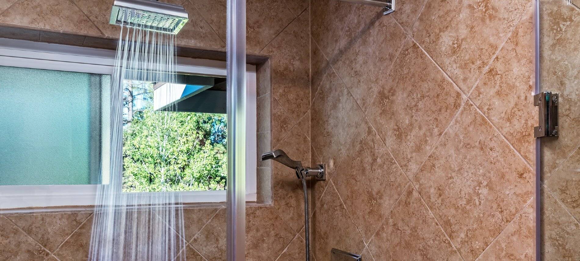 Luxurious stand up shower with brown tile, window to the outside and modern rainfall showerhead