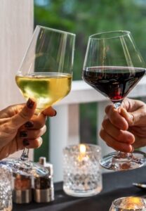 wine glasses clinking, one with red and one with white wine